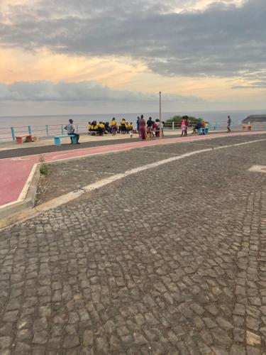a group of people sitting on benches by the water at Chez Lena, Appartement confortable 3 chambres in Praia