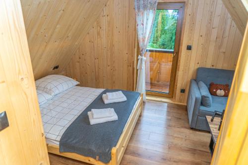 a bedroom with a bed and a couch and a window at Niedźwiedzia Chatka in Rzepiska