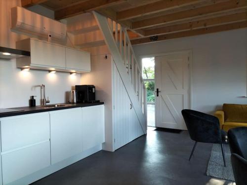 a kitchen with white cabinets and a table and chairs at De Heide in Wijnjewoude