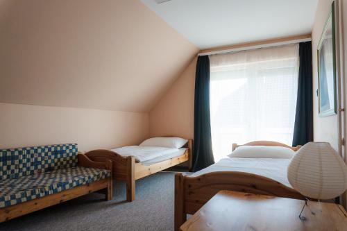 a room with two beds and a couch and a window at Tea Apartman Balatongyörök in Balatongyörök