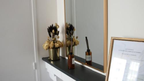 a shelf with a mirror and a vase with flowers at L'écrin de Camille et Marie in Bobigny