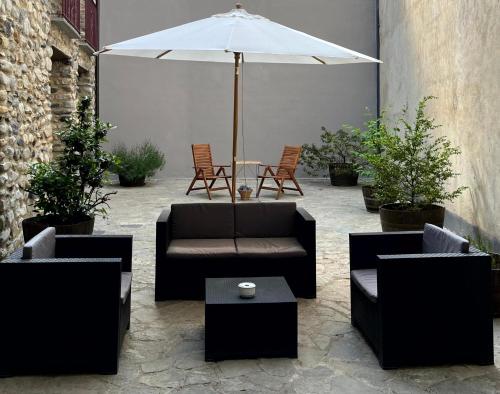 a patio with couches and a table with an umbrella at Casa Damian del Baile Apartamentos in Benasque