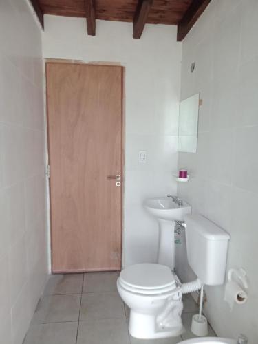 a bathroom with a toilet and a sink and a door at La Corzuela in Lozano