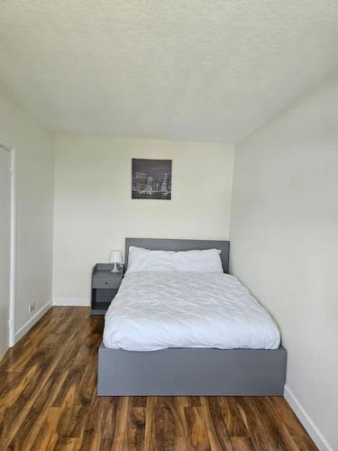 a bedroom with a white bed and a wooden floor at Feel at home away from home in Plumstead
