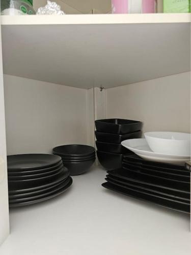 a bunch of black plates and bowls in a cabinet at Feel at home away from home in Plumstead