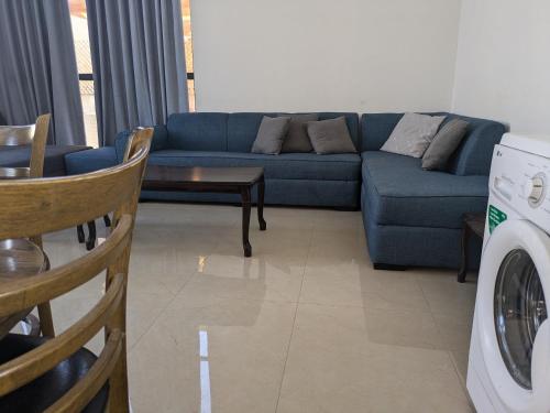 a living room with a blue couch and a washing machine at Aeropuerta Mini Villa - Private self check-in Layover near Amman Airport in Al Qasţal