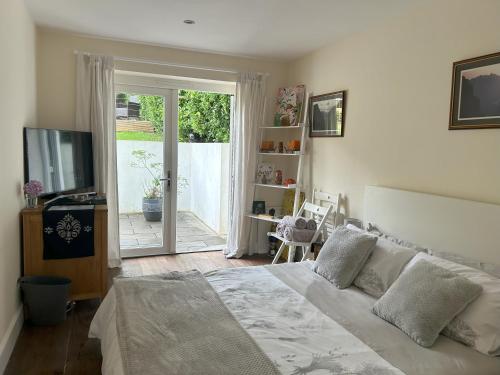 a bedroom with a bed and a sliding glass door at Sanctuary by the Sea with large room incl lounge area, bathroom, direct garden access & free parking in Rottingdean