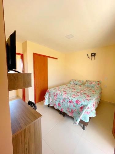 a bedroom with a bed and a flat screen tv at Nosso Chalé in Serra de São Bento