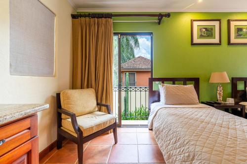 a bedroom with a bed and a chair and a window at Jade Coast 3- Private 5 Bedroom Villa in Tamarindo