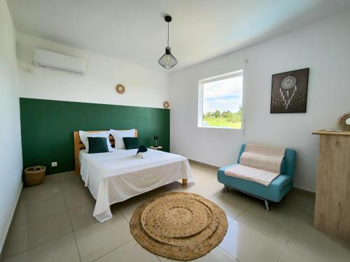 a bedroom with a bed and a chair and a window at Kukumi's House avec Piscine in Sainte-Anne