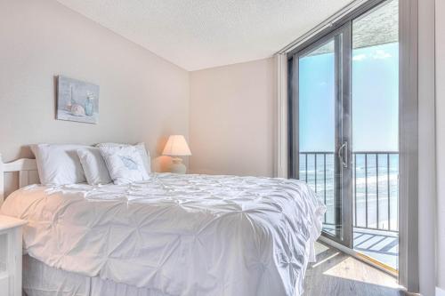 a white bedroom with a bed and a large window at Ocean Trillium 803 - A 1 Bedroom Condo With Beautiful Ocean Views in New Smyrna Beach