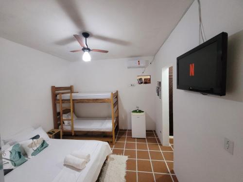 a living room with a bed and a flat screen tv at Aldeia Ubatuba in Ubatuba