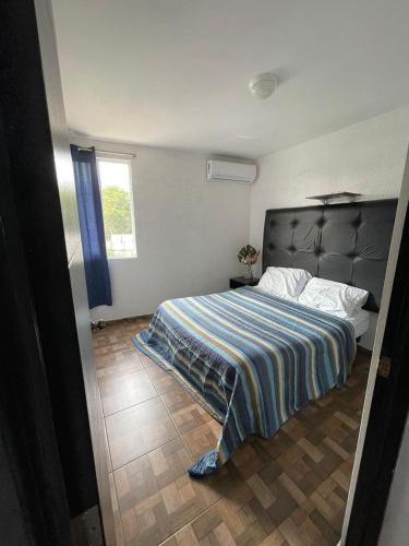 a bedroom with a bed with a striped blanket on it at Cómodo Depto frente a plaza Américas Xalapa Ver in El Castillo