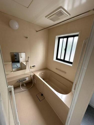 a bathroom with a bath tub and a window at Hiei Mountain House in Otsu