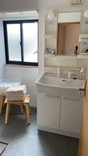 a white bathroom with a sink and a mirror at Hiei Mountain House in Otsu