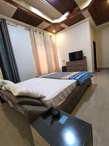 a bedroom with a bed and a table and a television at Kigali Mechatronics Villa in Kigali