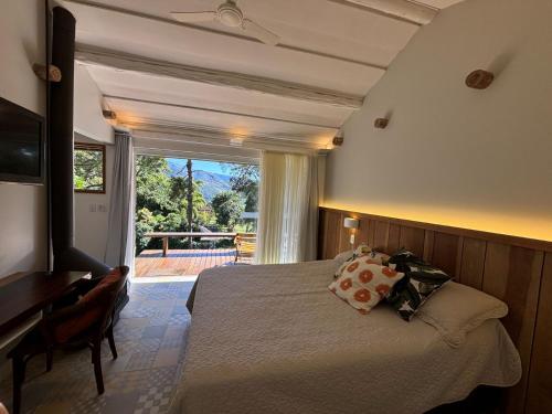 a bedroom with a bed and a desk and a window at Auberge Suisse Pousada in Nova Friburgo