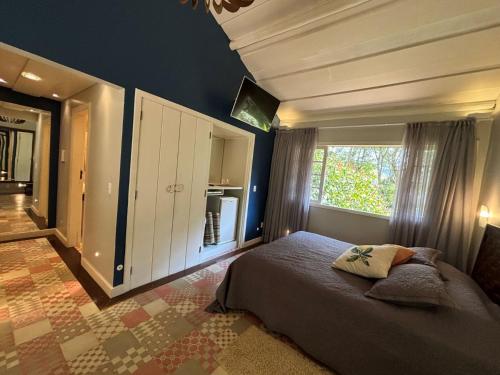 a bedroom with a bed and a large window at Auberge Suisse Pousada in Nova Friburgo