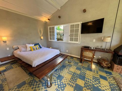 a bedroom with a bed and a table and a window at Auberge Suisse Pousada in Nova Friburgo