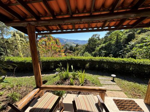 a patio with two chairs and a pergola at Auberge Suisse Pousada in Nova Friburgo