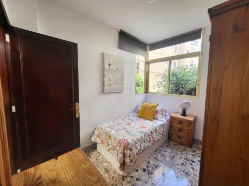 ein kleines Schlafzimmer mit einem Bett und einem Fenster in der Unterkunft Affordable holiday accommodation for large families and groups at Las Canteras beach with 3 Bedrooms and Free Parking in Las Palmas de Gran Canaria