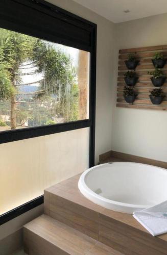 a bath tub in a bathroom with a window at Room Hotel Wanderlust in Campos do Jordão