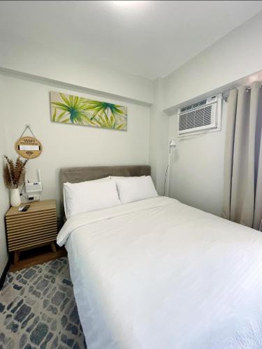 a bedroom with a large white bed and a fan at 1 BR Condo with balcony in Verdon Parc with Sea View in Sanghay