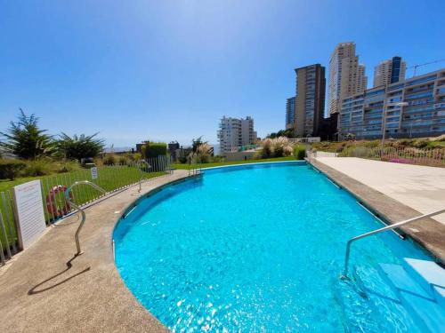 Una gran piscina azul con edificios al fondo. en Apt Costa de Montemar, Concón, en Concón