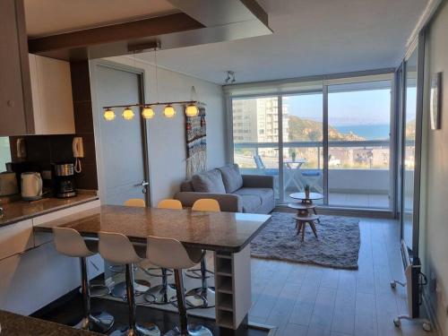 Una cocina y una sala de estar con mesa y sillas. en Apt Costa de Montemar, Concón, en Concón