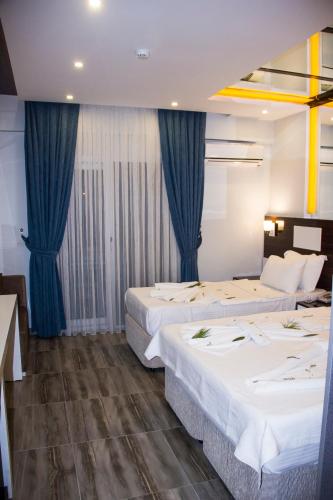 two beds in a hotel room with blue curtains at Pamukkale Termal Ece Otel in Pamukkale
