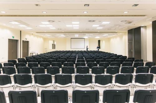 an empty lecture hall with chairs and a man standing on a podium at Gotthard Therme Hotel & Conference in Szentgotthárd