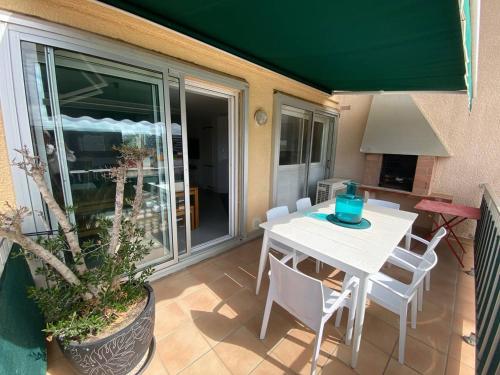 une table blanche et des chaises sur une terrasse avec une fenêtre dans l'établissement T3 Confort avec Clim et Wifi, Terrasse, 300m Commerces, Plage à Proximité, Parking Privé - FR-1-81-623, au Barcarès