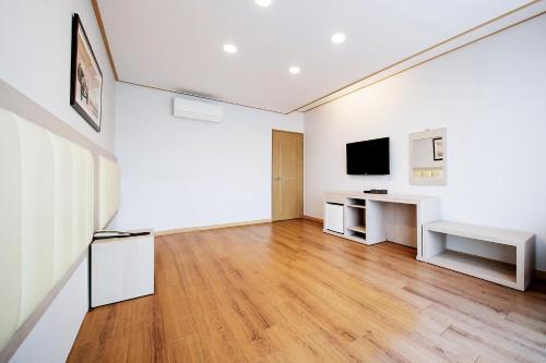 a white room with a desk and a tv at Shin Shin Hotel Jeju City in Jeju