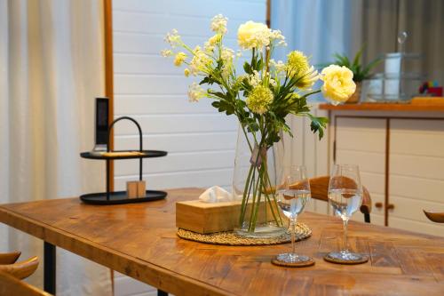 a table with a vase of flowers and wine glasses at NEW OPEN!Popular beaches are within a 5minute walk in Inbu