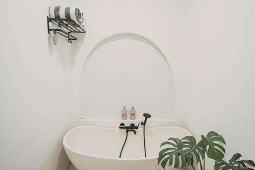 a bath tub in a white bathroom with a mirror at Bohemian Jogja Villas with Private Pool in Kejayan