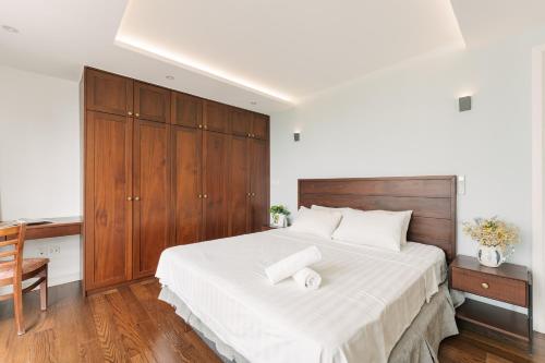 a bedroom with a large bed and a wooden cabinet at D’Leroi Soleil - Westlake Suite & Apartment in Hanoi