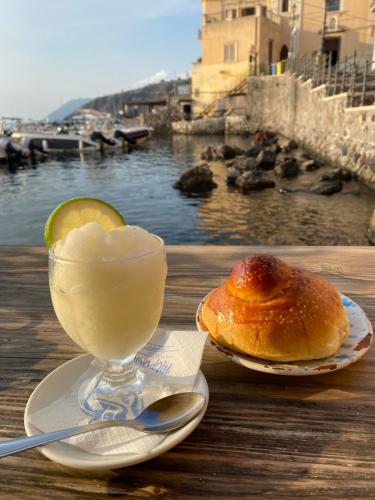 a drink and a pastry on a table with a view of the water at Via Roma 55 in Lipari