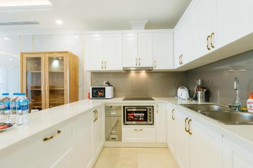 a kitchen with white cabinets and a sink at D’Leroi Soleil - Westlake Suite & Apartment in Hanoi