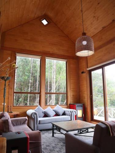 a living room with a couch and a table at Refugio Mayapehue, Lago Natri Chiloé in El Púlpito