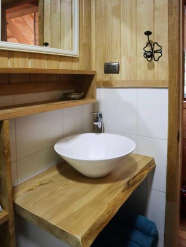 a bathroom with a white bowl sink on a wooden counter at Refugio Mayapehue, Lago Natri Chiloé in El Púlpito