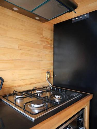 a stove top in a kitchen with wooden walls at Refugio Mayapehue, Lago Natri Chiloé in El Púlpito