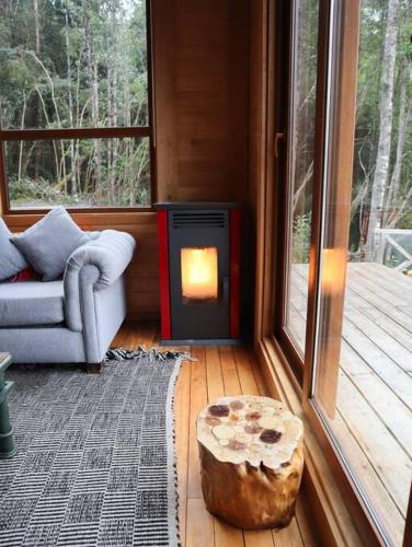 a living room with a log and a fireplace at Refugio Mayapehue, Lago Natri Chiloé in El Púlpito