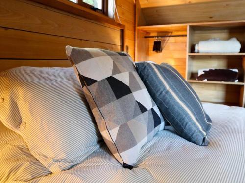 a bed with two pillows on top of it at Refugio Mayapehue, Lago Natri Chiloé in El Púlpito