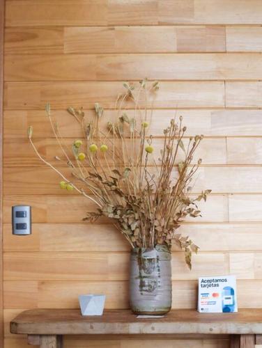a vase with a plant on a wooden table at Refugio Mayapehue, Lago Natri Chiloé in El Púlpito