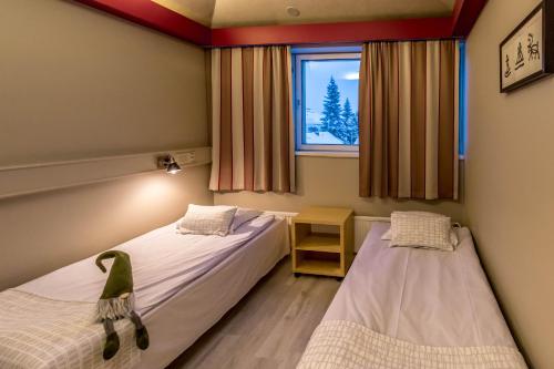 two beds in a room with a window at Santa's Hotel Rudolf in Rovaniemi