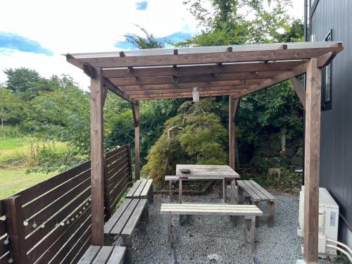 a wooden pergola with a picnic table and a bench at 富士晴 Guest House in Minamitsuru