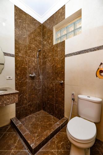 a bathroom with a toilet and a shower at Maharani Guest House in Yogyakarta