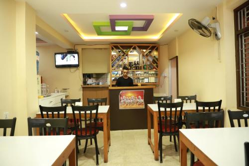 une salle à manger avec des tables et des chaises et un barman dans l'établissement HotelKTM, à Katmandou