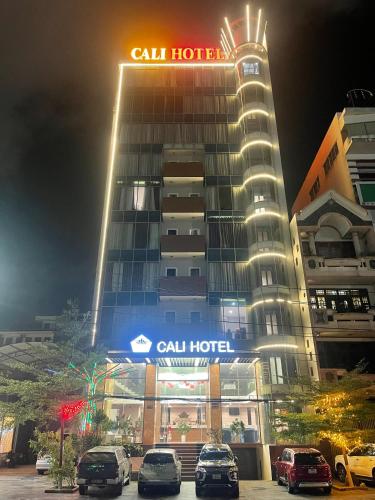 a tall hotel with cars parked in front of it at Cali Hotel Quy Nhơn in Quy Nhon