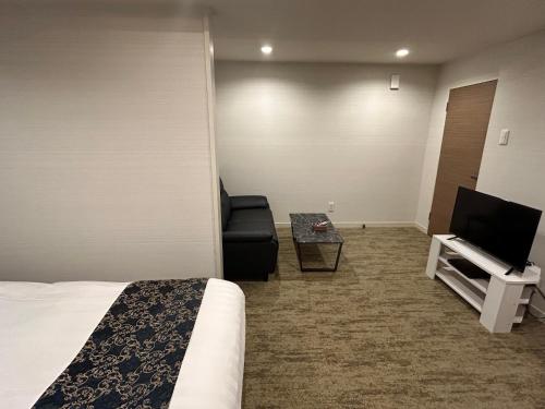 a hotel room with a bed and a chair and a television at ホテルアイエス in Yokohama